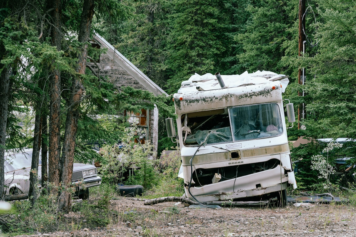 Damaged rv and abandoned house in forest